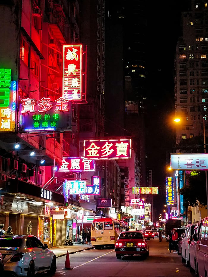 A busy city street at night with neon lights.